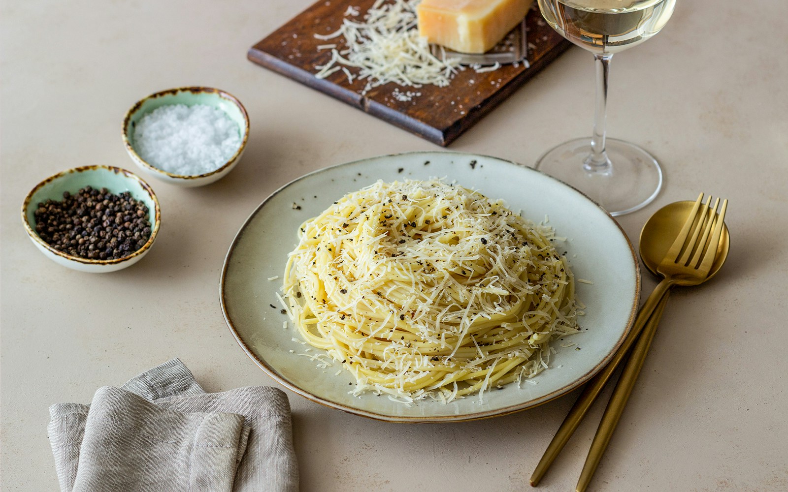 Spaghetti cacio e pepe with grated cheese and black pepper on a plate.