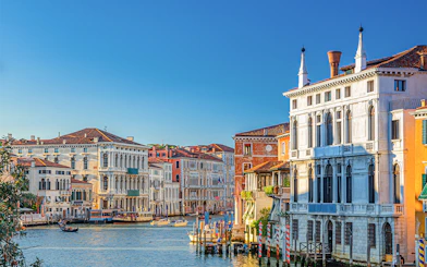 Ca' Rezzonico along the Grand Canal in Venice with gondolas and historic buildings.