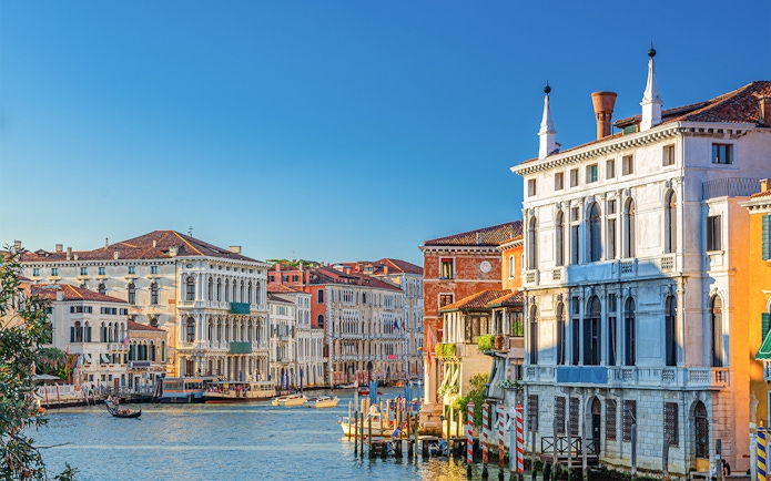 Ca' Rezzonico along the Grand Canal in Venice with gondolas and historic buildings.