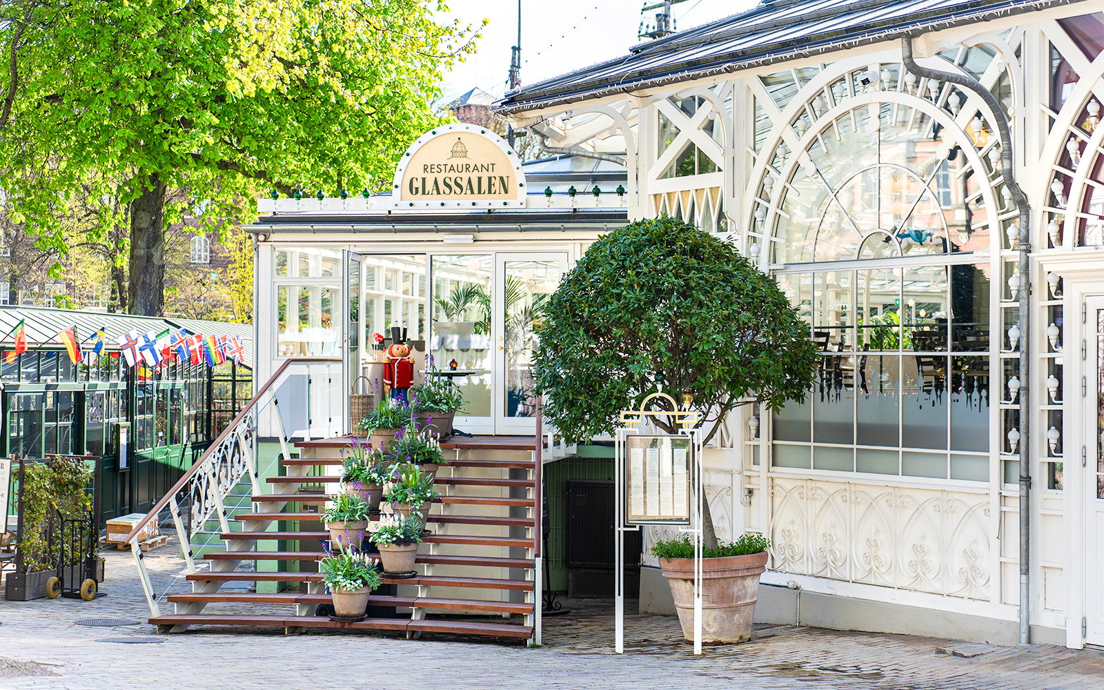 Glass restaurant entrance at Tivoli Gardens, Copenhagen with potted plants and decorative facade.