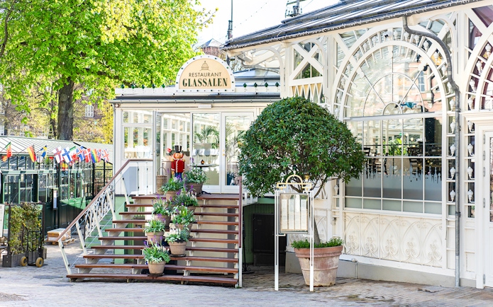 Glass restaurant entrance at Tivoli Gardens, Copenhagen with potted plants and decorative facade.