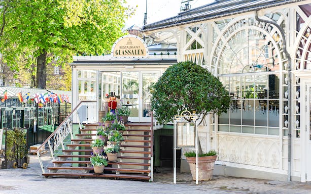 Glass restaurant entrance at Tivoli Gardens, Copenhagen with potted plants and decorative facade.