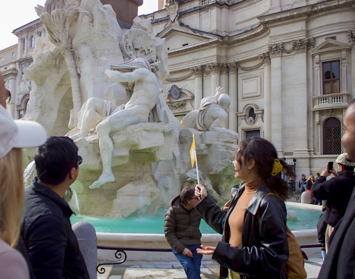 Tourists viewing the Fountain of the Four Rivers in Piazza Navona, Rome.