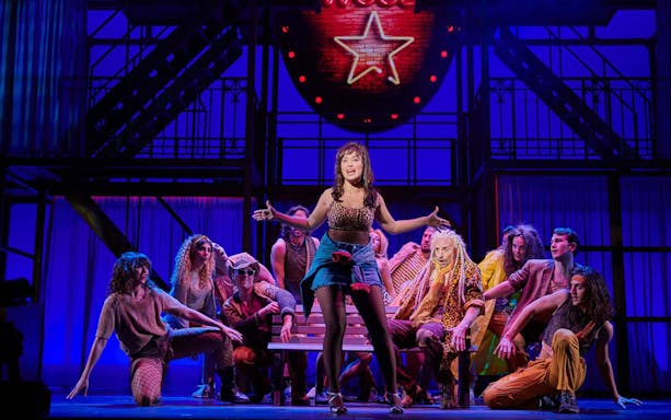 Performers on stage during "Pretty Woman - El musical" with vibrant lighting.