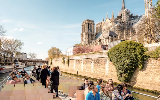Seine River cruise with tourists near Notre-Dame Cathedral in Paris.
