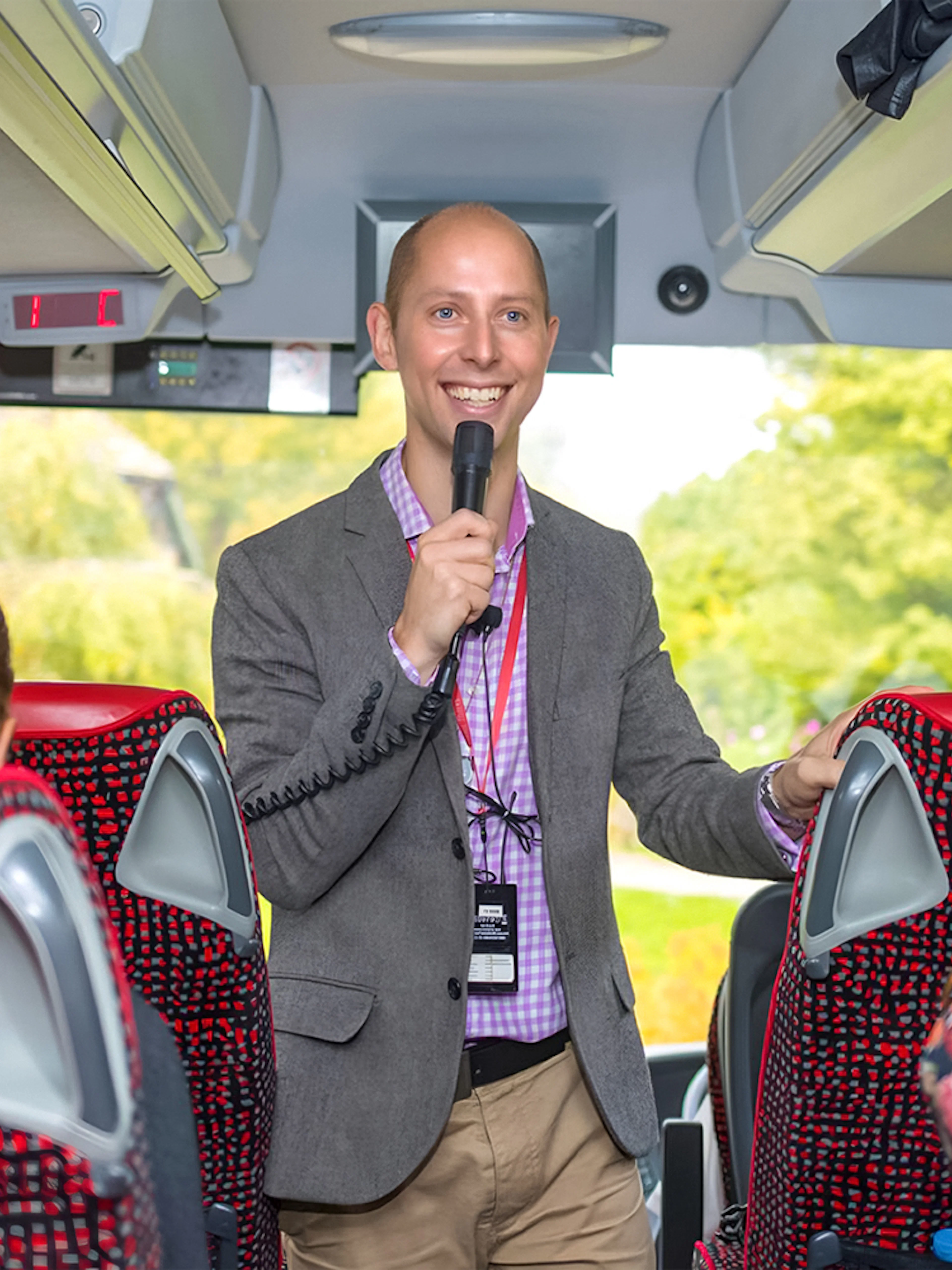 Tour guide speaking to passengers on a coach transfer.