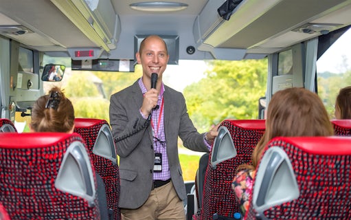 Tour guide speaking to passengers on a coach transfer.