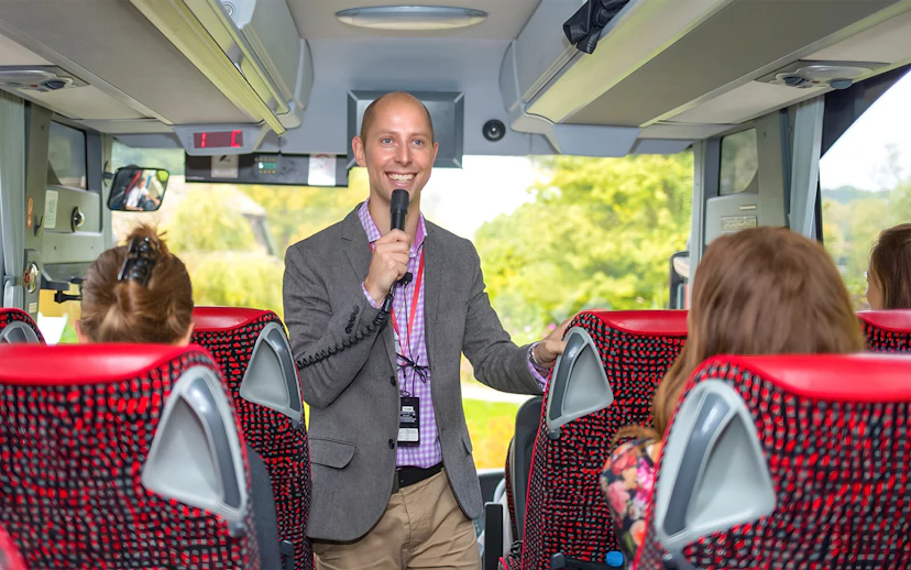 Tour guide speaking to passengers on a coach transfer.