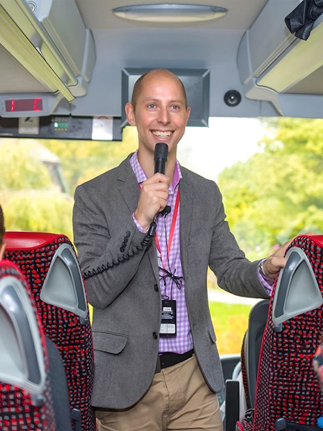 Tour guide speaking to passengers on a coach transfer.