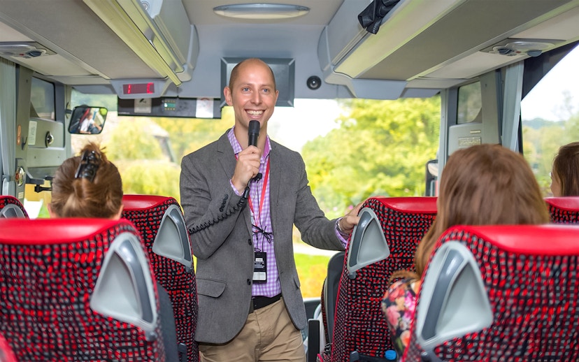 Tour guide speaking to passengers on a coach transfer.
