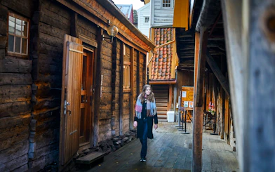 Guest walking through historic wooden alley in Bergen, Norway.