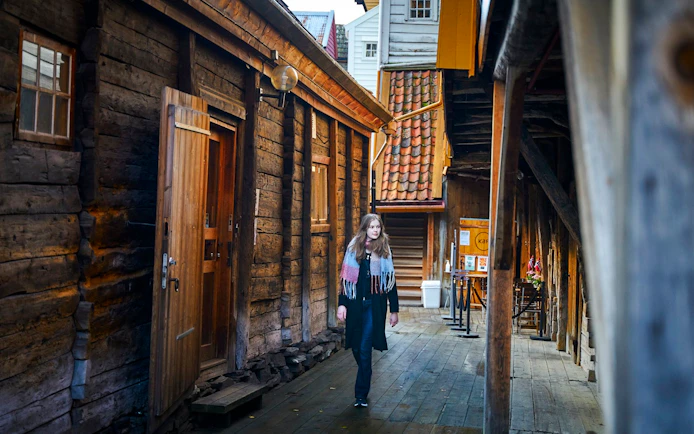 Guest walking through historic wooden alley in Bergen, Norway.