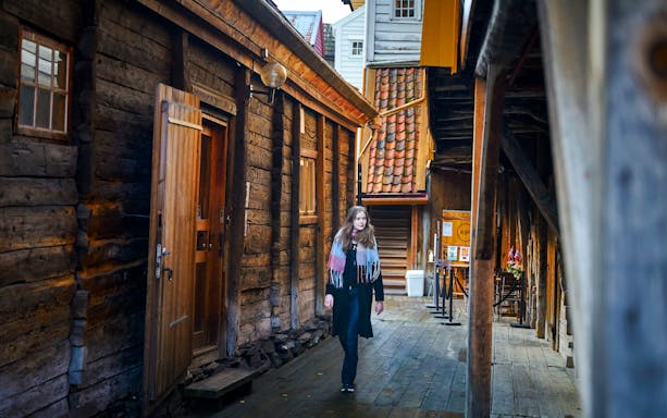 Guest walking through historic wooden alley in Bergen, Norway.