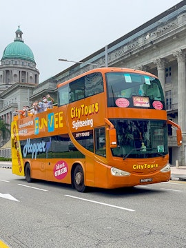 Open-top FunVee bus on a city tour in Singapore with passengers waving.