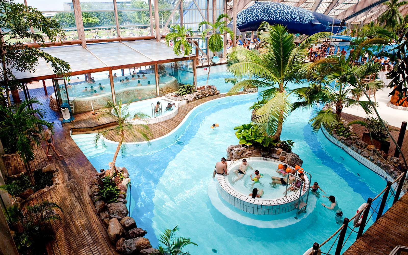 Indoor water park with pools and palm trees at Aquaboulevard de Paris.