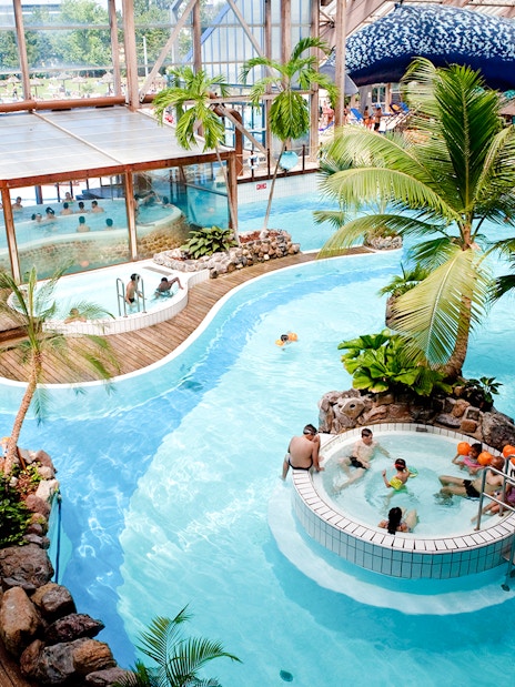 Indoor water park with pools and palm trees at Aquaboulevard de Paris.