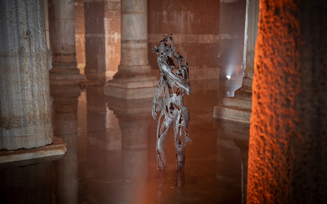 Sculpture in Basilica Cistern, Istanbul, surrounded by ancient columns and water reflections.