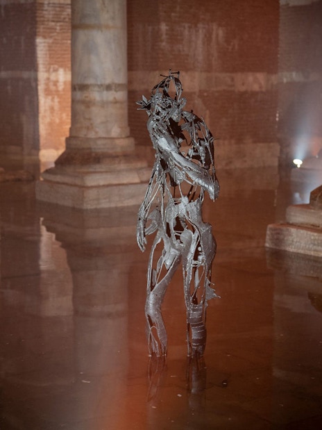 Sculpture in Basilica Cistern, Istanbul, surrounded by ancient columns and water reflections.