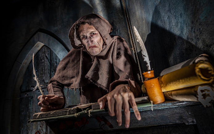 Monk in brown robe with quill at York Dungeon's Vengeance of the Vikings exhibit.