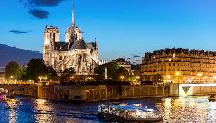 Notre Dame de Paris with cruise ship on Seine river at night in Paris