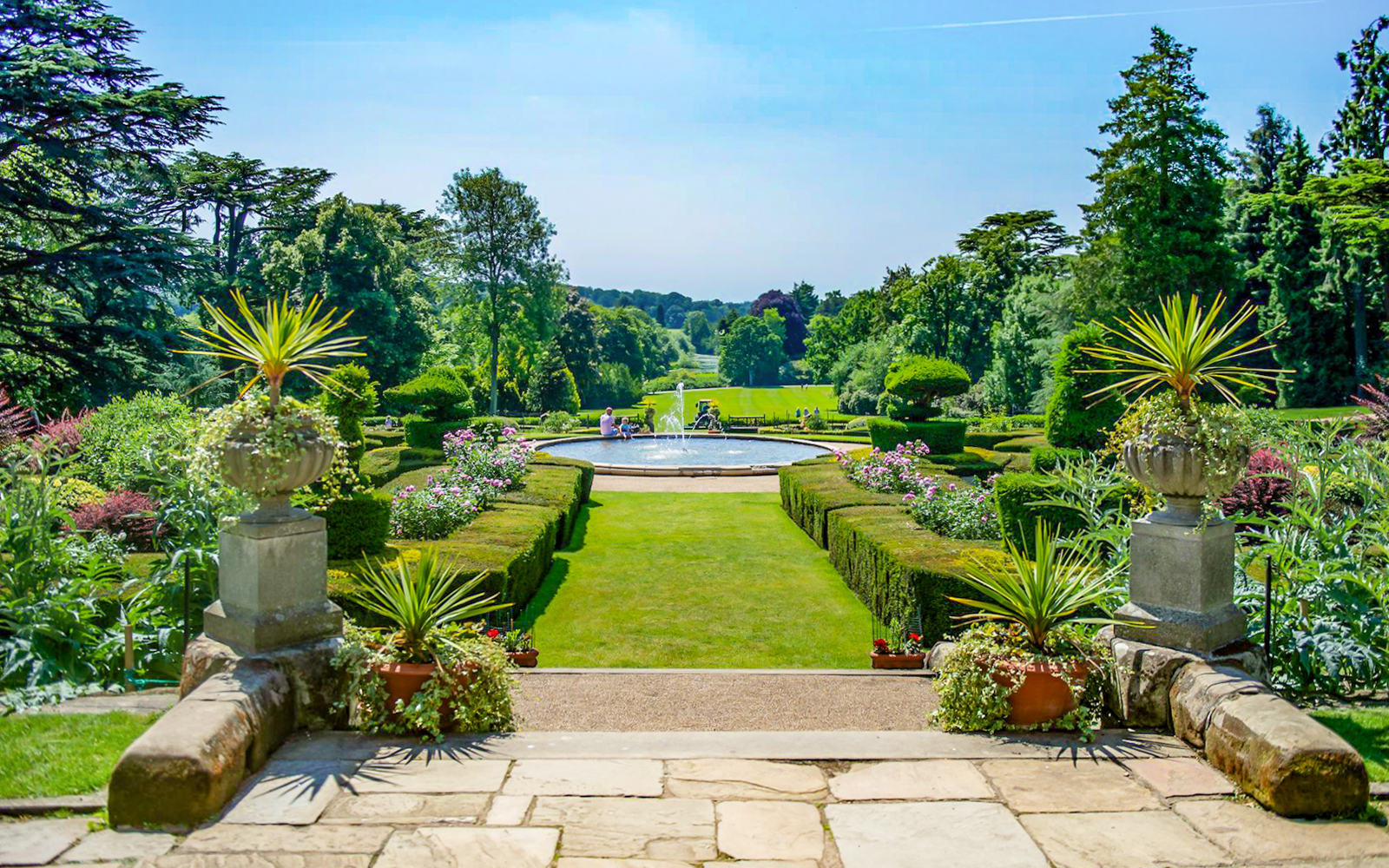 Warwick Castle gardens with fountain and manicured hedges in the background.