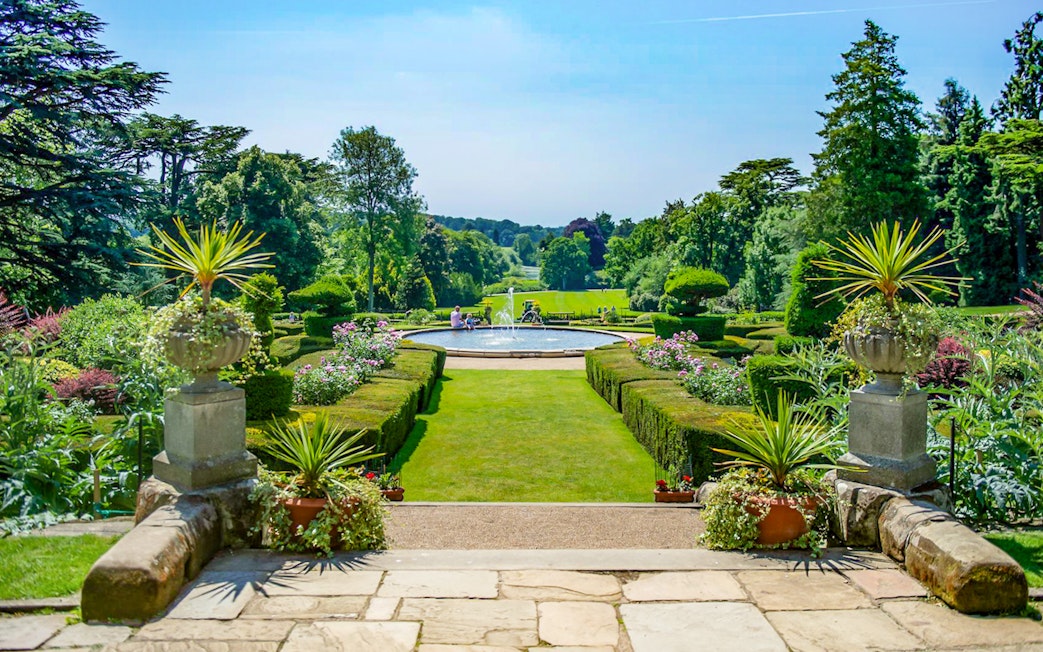 Warwick Castle gardens with fountain and manicured hedges in the background.