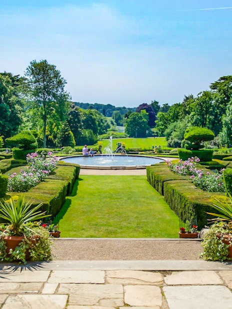 Warwick Castle gardens with fountain and manicured hedges in the background.