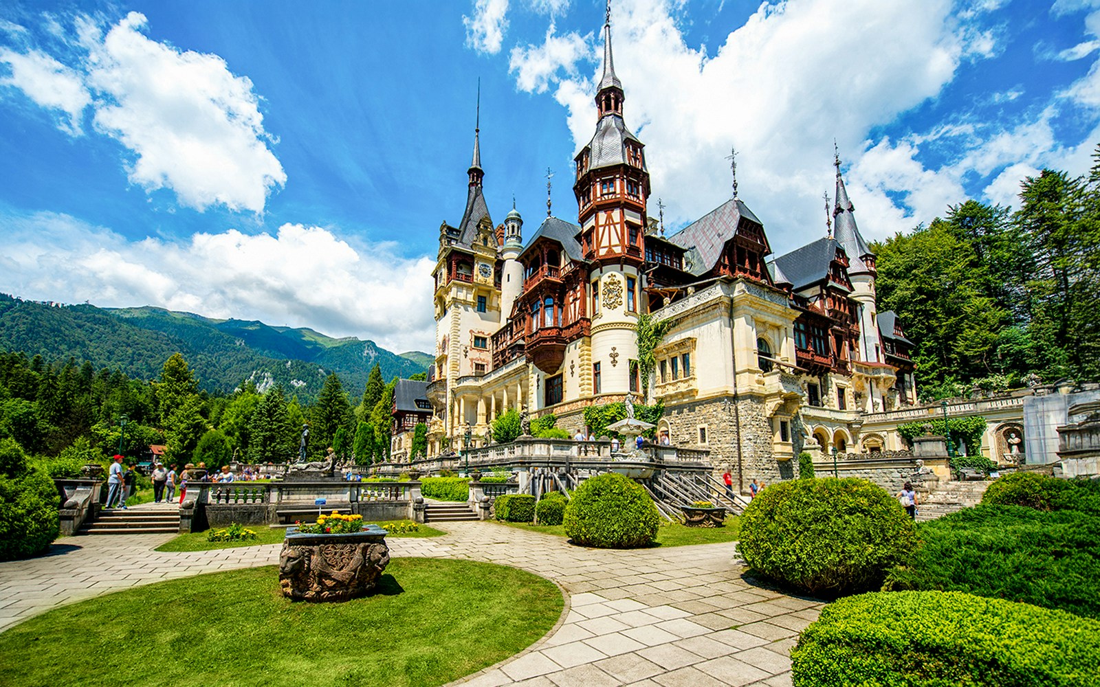 Peles Castle exterior with gardens and Carpathian Mountains in Sinaia, Romania.