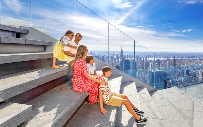 Family enjoying view from Edge Observation Deck, New York City, with skyline and Empire State Building.
