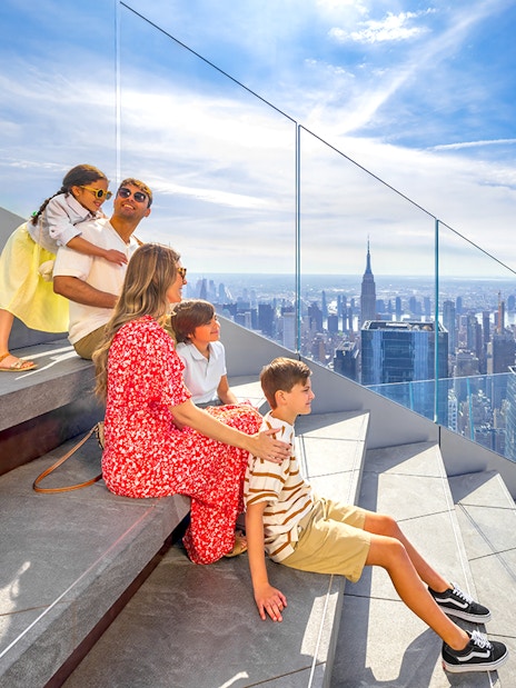 Family enjoying view from Edge Observation Deck, New York City, with skyline and Empire State Building.