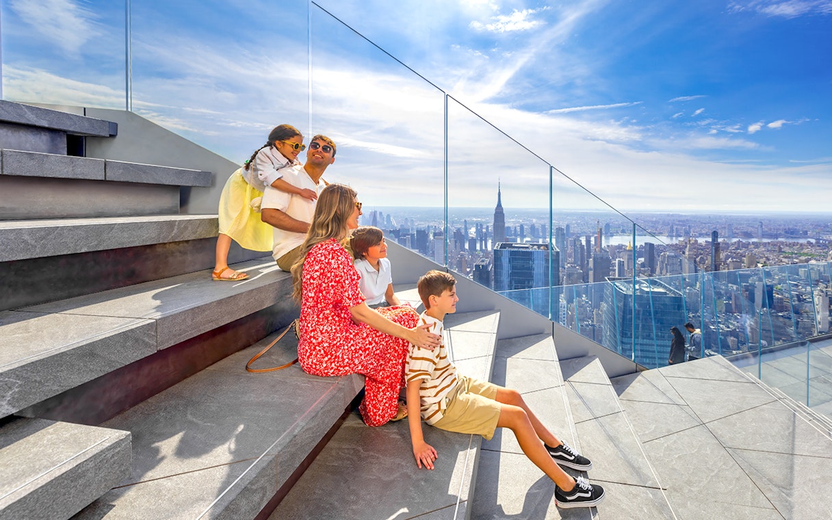 Family enjoying view from Edge Observation Deck, New York City, with skyline and Empire State Building.