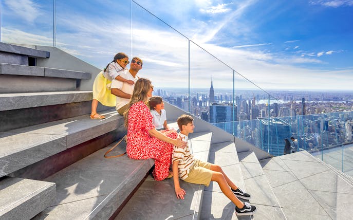 Family enjoying view from Edge Observation Deck, New York City, with skyline and Empire State Building.