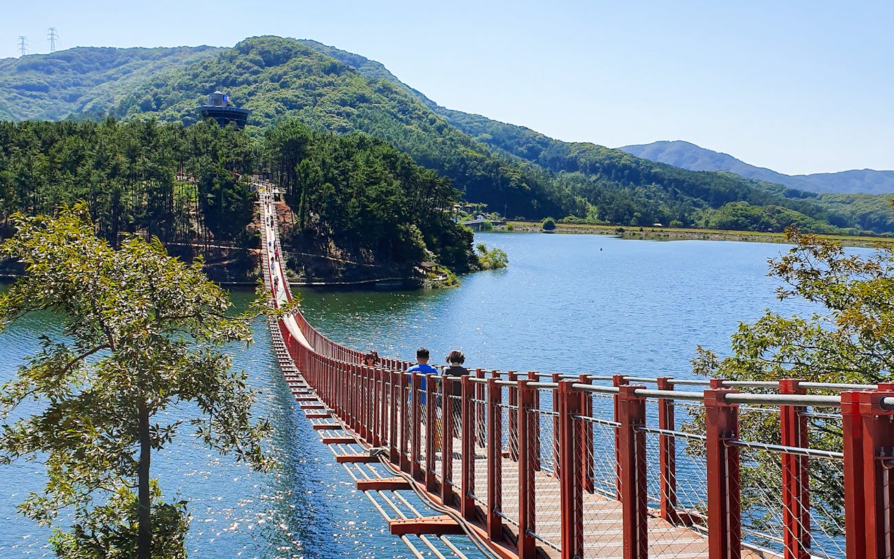 Suspension bridge over a lake with mountains in the background on the Korean DMZ Tour from Seoul.