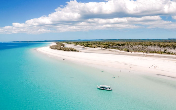 Tour boat anchored near white sand beach on an island in Hervey Bay.