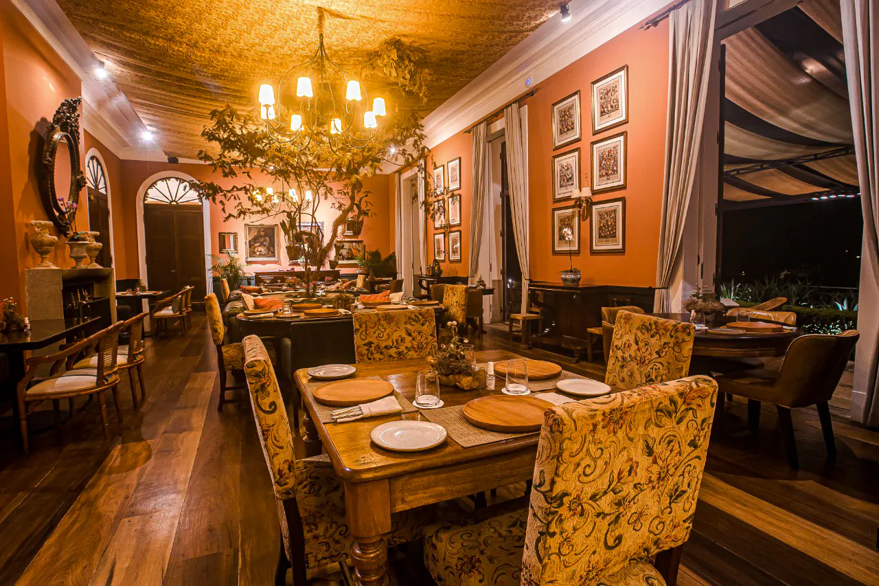 Dining room in a historic restaurant in Petrópolis, Rio de Janeiro, with elegant decor and warm lighting.