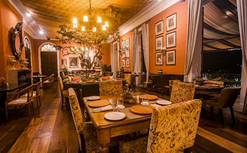Dining room in a historic restaurant in Petrópolis, Rio de Janeiro, with elegant decor and warm lighting.