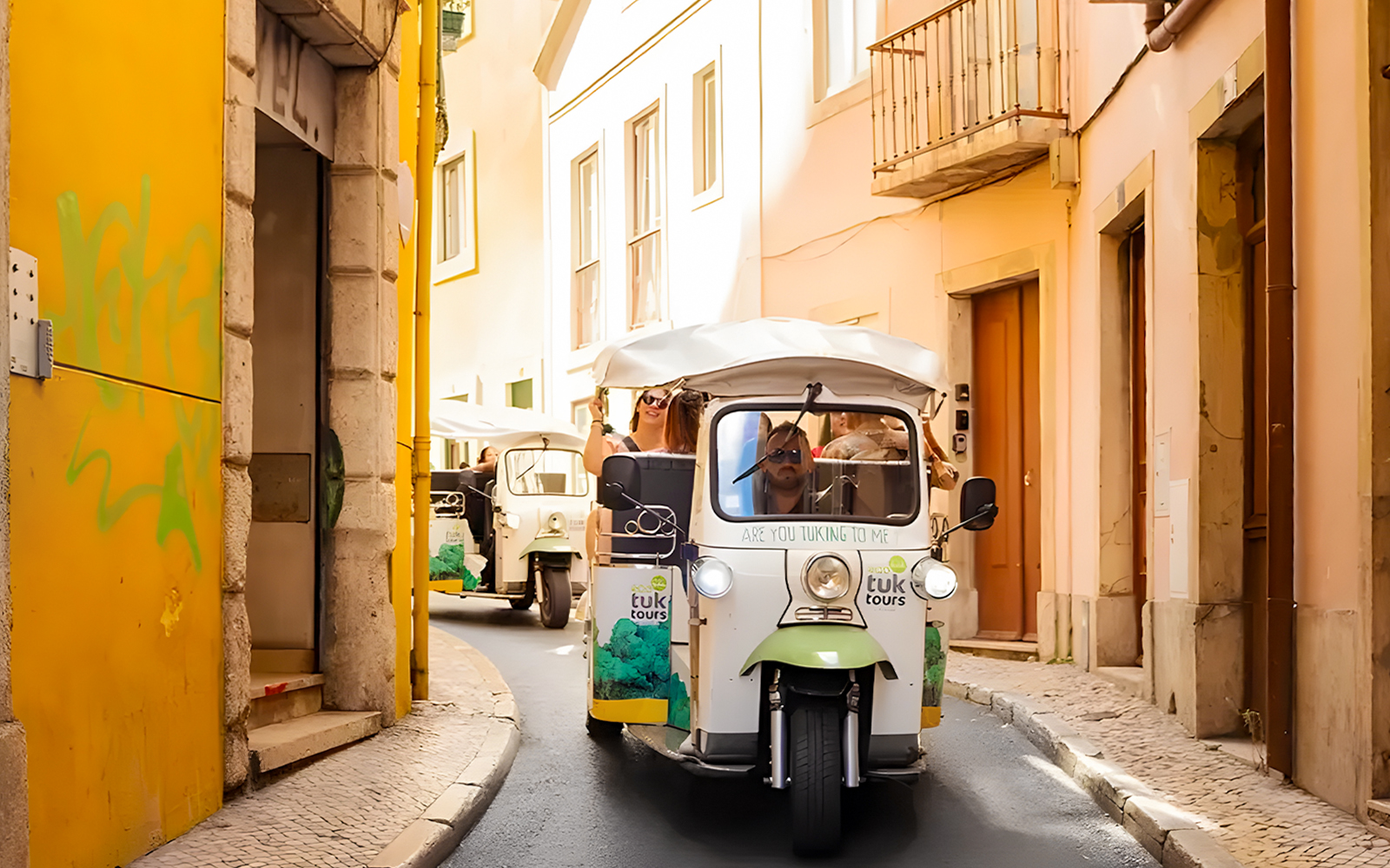 Tourist on eco tuk tuk navigating narrow streets in Lisbon.