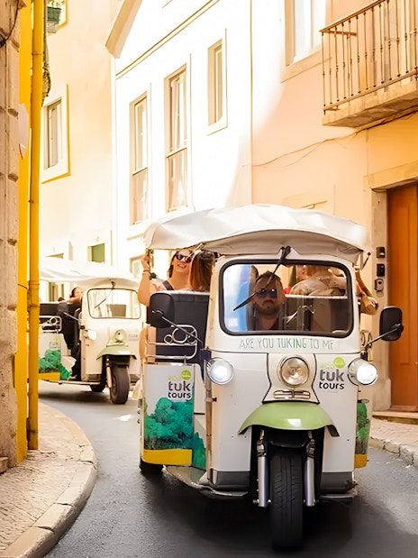 Tourist on eco tuk tuk navigating narrow streets in Lisbon.