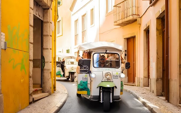 Tourist on eco tuk tuk navigating narrow streets in Lisbon.