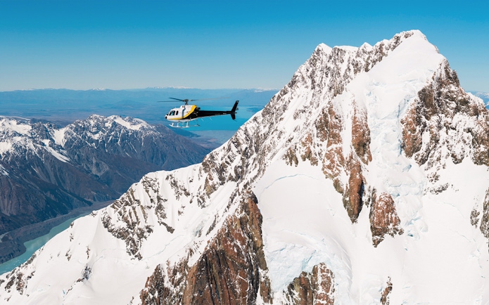 Helicopter flying near snow-covered Mt Cook with Lake Pukaki in the background.