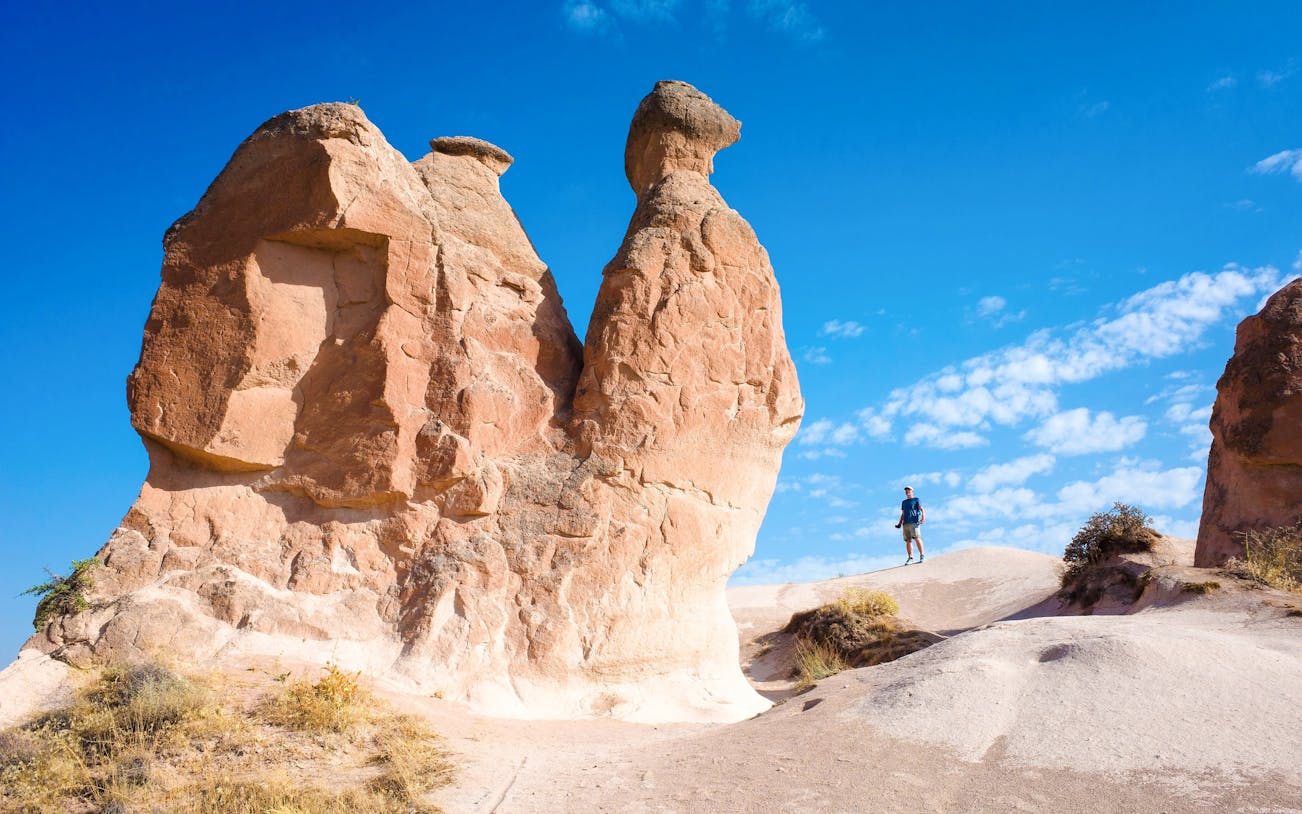 Rock formations in Devrent Valley, Cappadocia with a person walking nearby.