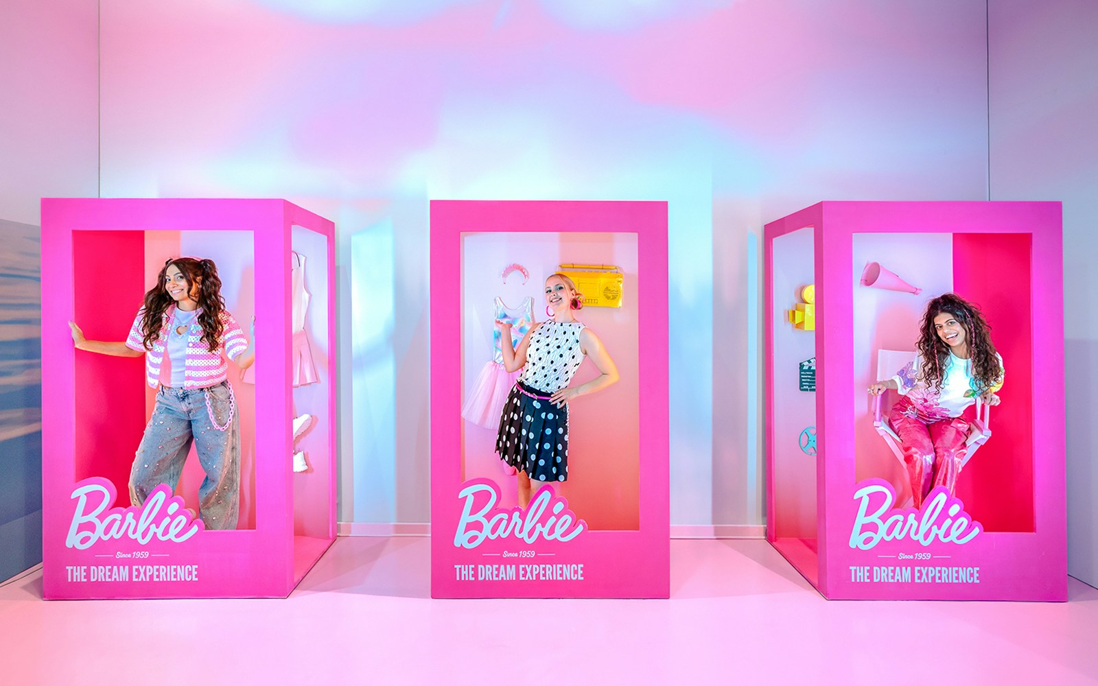 Guests posing inside life-sized Barbie boxes at The Dream Experience.