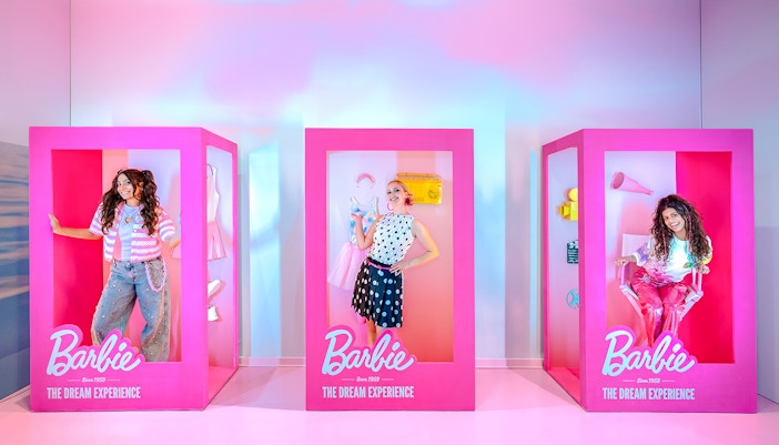 Guests posing inside life-sized Barbie boxes at The Dream Experience.
