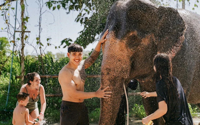 Visitors splashing water with a rescued elephant at Phuket Elephant Care.