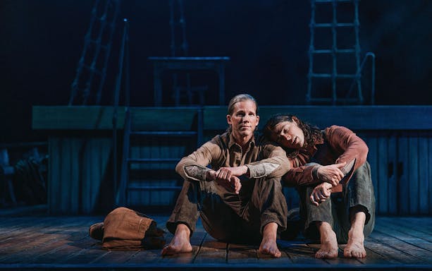 Two people sitting on a ship deck, one resting their head on the other's shoulder, evoking a scene from "Swept Away.