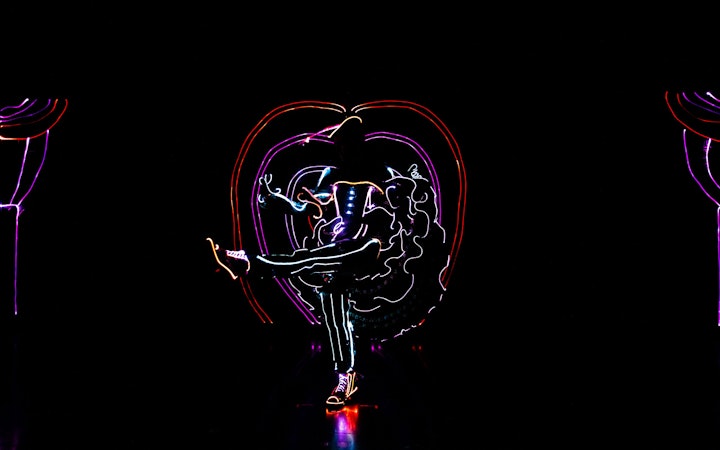 Performer in illuminated costume dancing in iLuminate show.