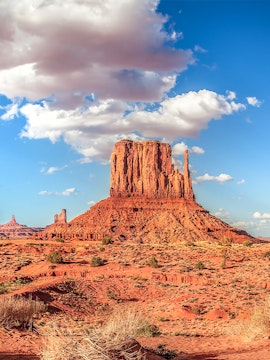 Panoramic view of Monument Valley's iconic buttes under a blue sky, USA.