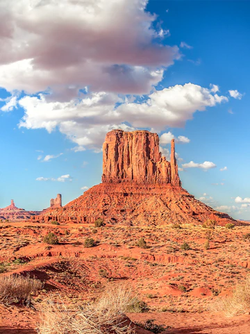 Panoramic view of Monument Valley's iconic buttes under a blue sky, USA.