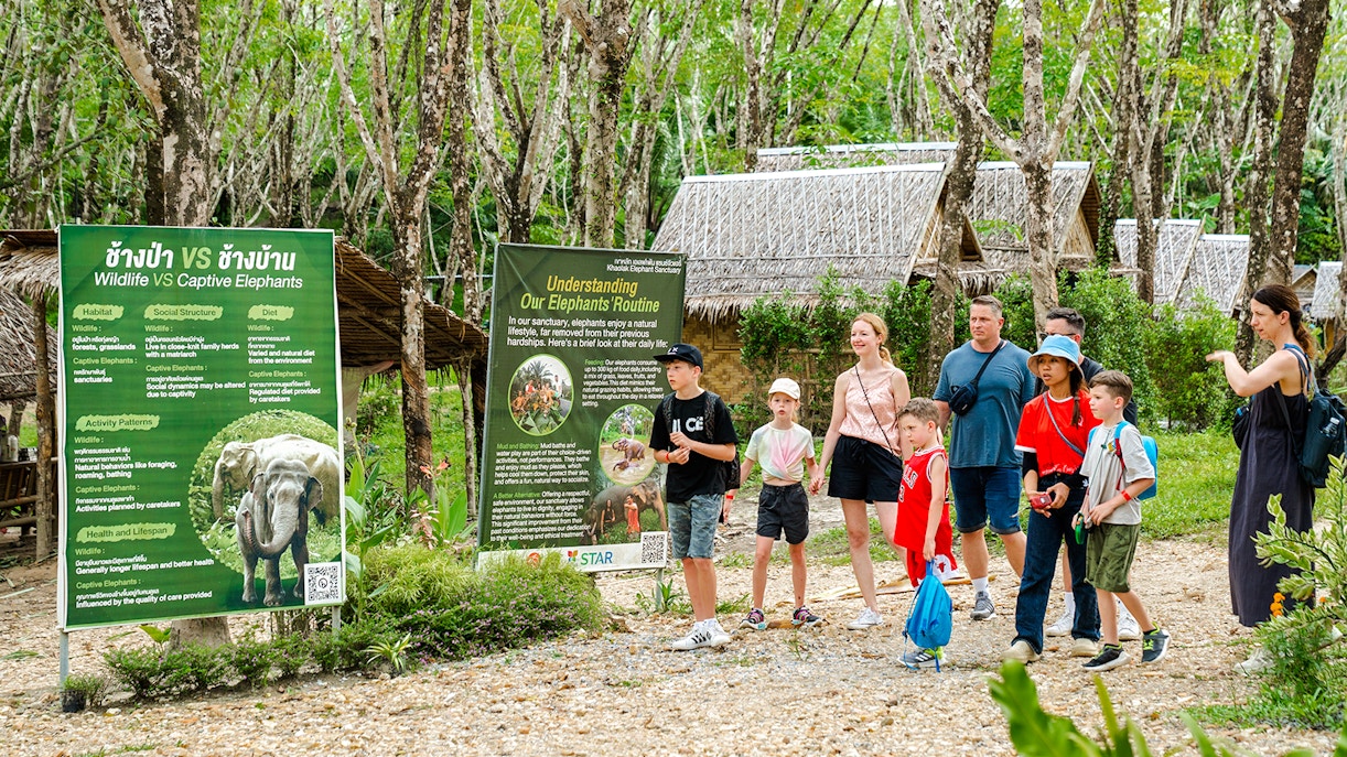 Visitors at Khaolak Ethical Elephant Sanctuary reading educational signs.