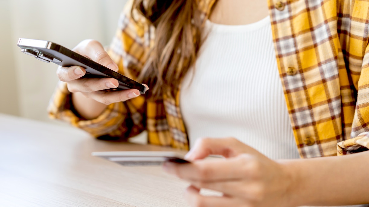 Person using a smartphone and credit card for online booking.